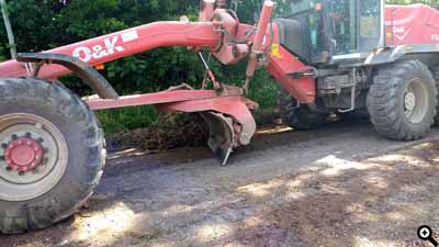 Ein Grader profiliert einen Hauptweg. Mit dem Schar wird das abfallende Profil hergestellt.